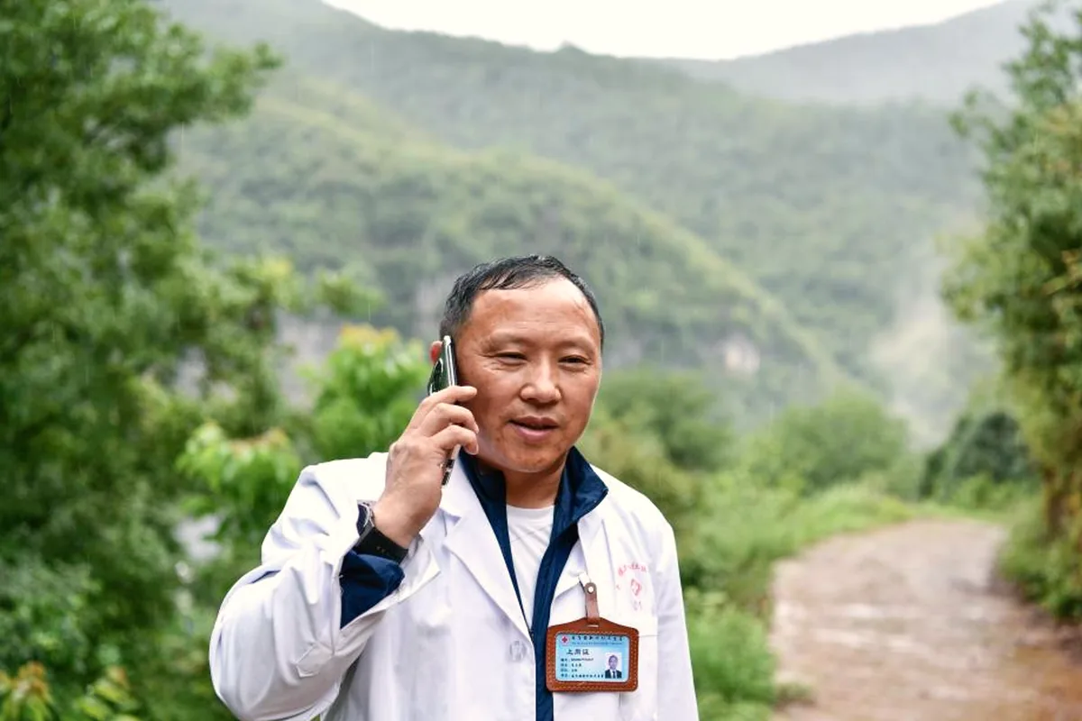 乡村家庭医生在村道上电话随访，入户服务途中